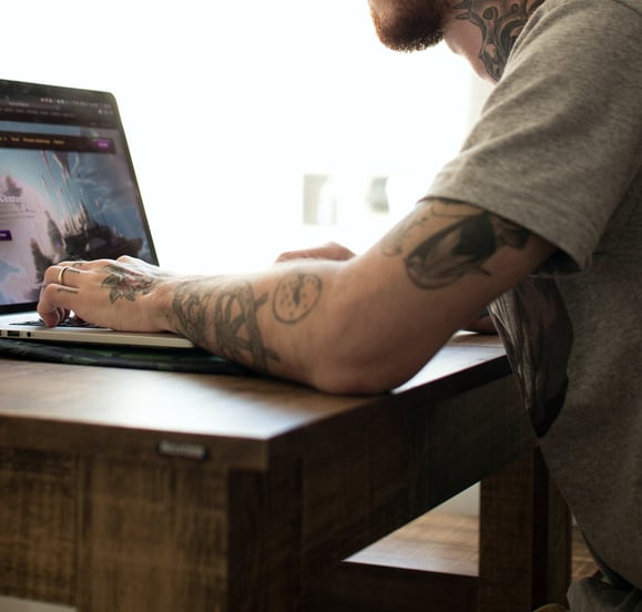 man at his computer, at a wooden desk