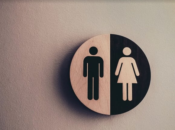 Black and white wooden, circular toilet sign. 